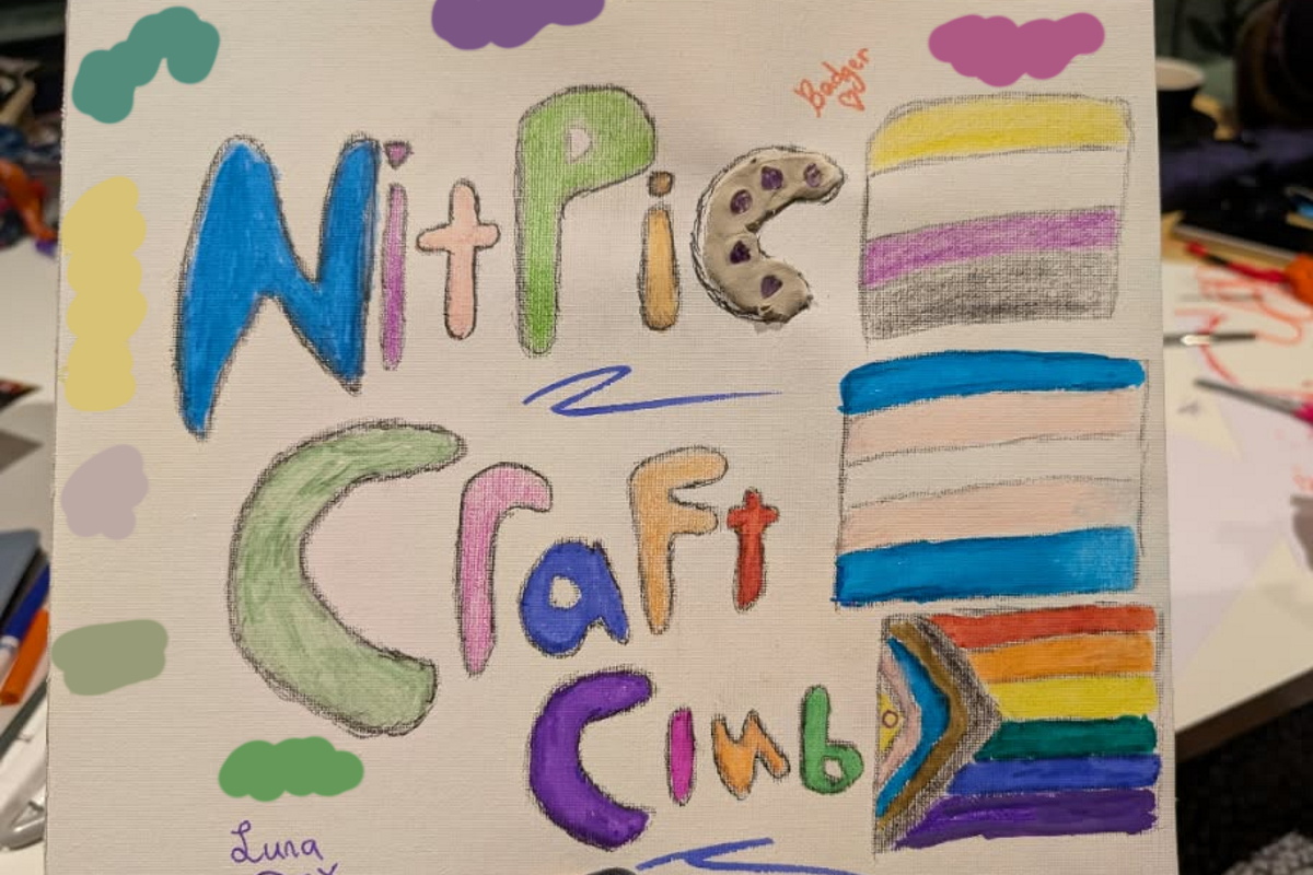 A sign which reads 'NITPIC craft club', and has trans, intersex, and non-binary flags